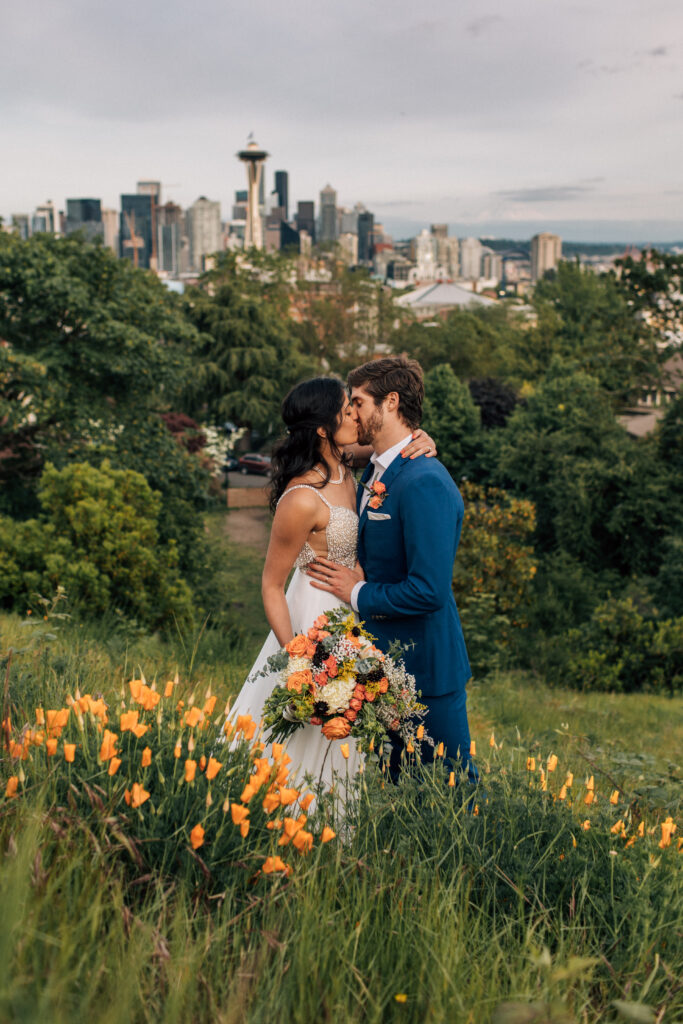 wedding couple kissing with flowers in foreground and seattle behind